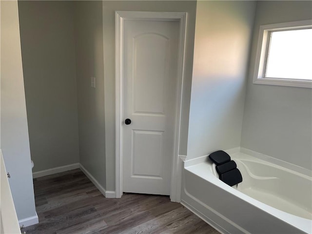 bathroom featuring hardwood / wood-style flooring and a tub to relax in