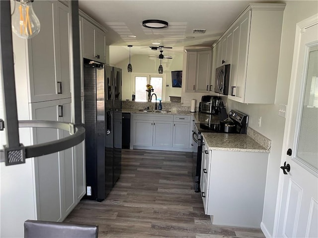 kitchen with pendant lighting, sink, light stone counters, dark hardwood / wood-style floors, and appliances with stainless steel finishes