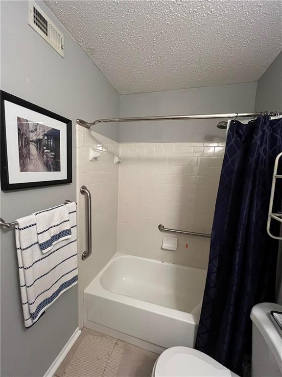 1251 Henckley Ave Unit 109, Mobile, AL 36609 - full bathroom with a textured ceiling, toilet, shower / bath combo with shower curtain, and tile patterned flooring