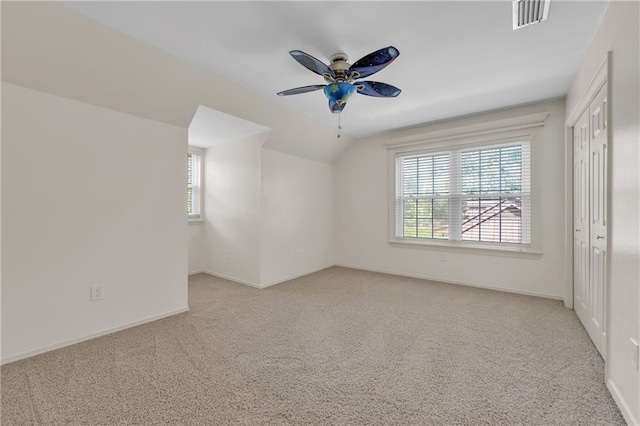 empty room featuring light carpet, ceiling fan, baseboards, visible vents, and lofted ceiling