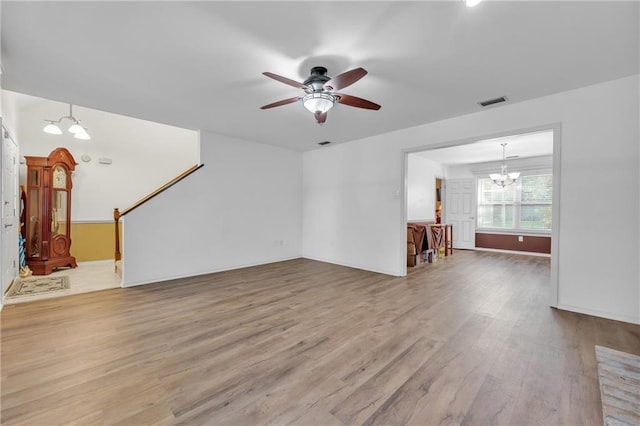 unfurnished living room featuring visible vents, baseboards, wood finished floors, and ceiling fan with notable chandelier