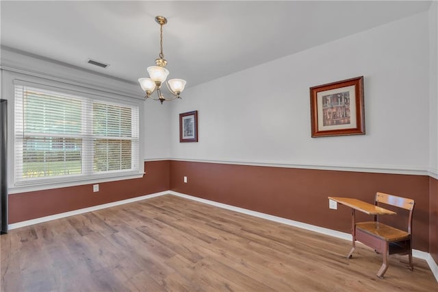 unfurnished room with baseboards, visible vents, wood finished floors, and a notable chandelier
