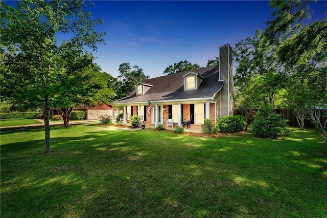 cape cod-style house with a porch, a front yard, a chimney, and fence