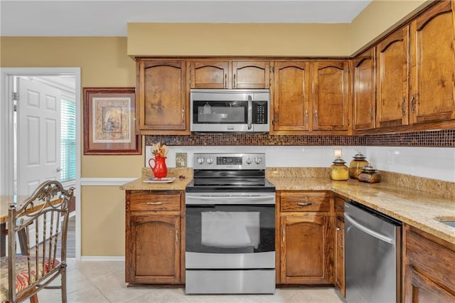 kitchen with stainless steel appliances, backsplash, and brown cabinets
