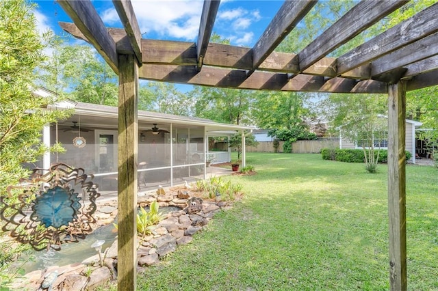 view of yard with fence, ceiling fan, a pergola, and a sunroom
