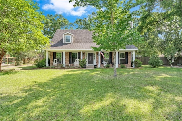 new england style home with brick siding, fence, a porch, and a front yard