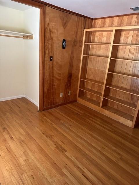 unfurnished bedroom featuring hardwood / wood-style floors and wood walls