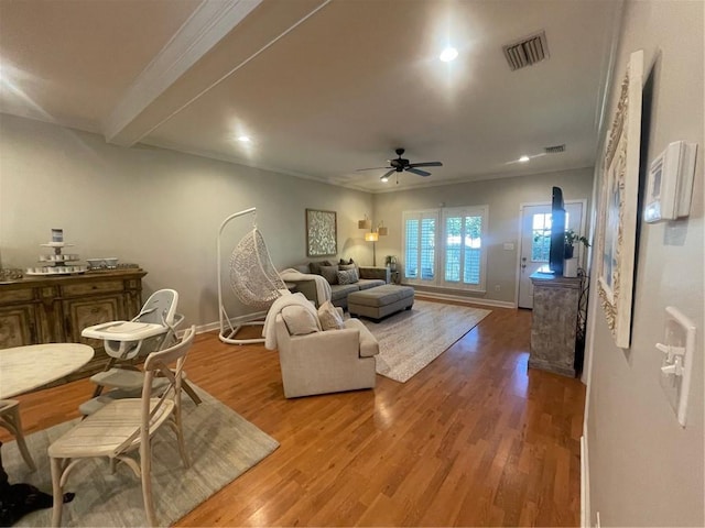 living area featuring baseboards, visible vents, ceiling fan, and wood finished floors