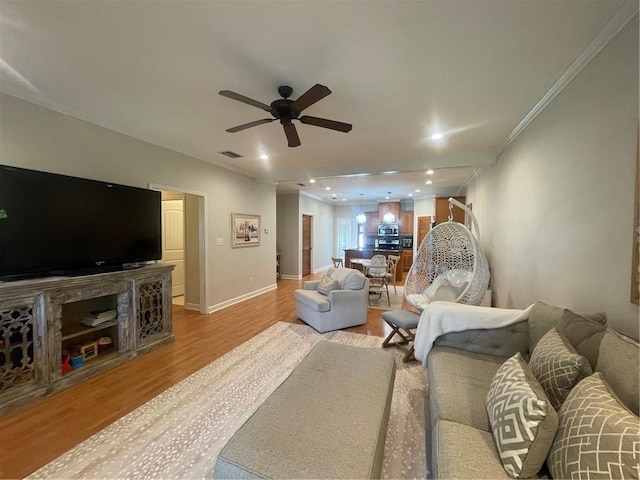 living room with a ceiling fan, baseboards, visible vents, light wood-style floors, and ornamental molding