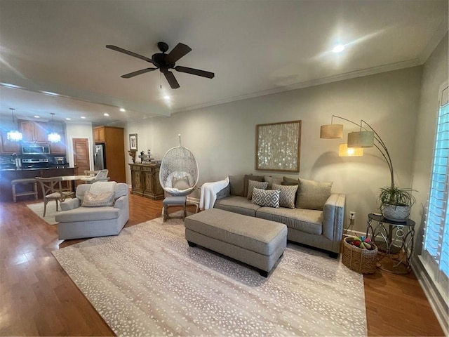 living area with ceiling fan, recessed lighting, wood finished floors, and crown molding