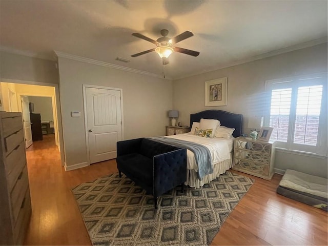 bedroom with ornamental molding, wood finished floors, and visible vents