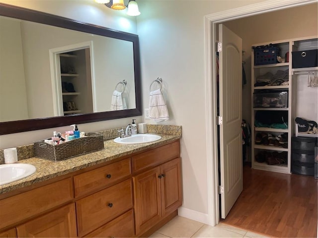 bathroom with double vanity, a spacious closet, and a sink