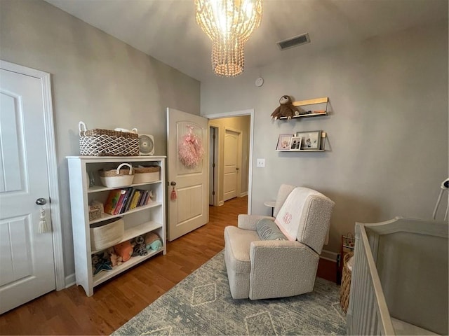 living area featuring an inviting chandelier, visible vents, and wood finished floors