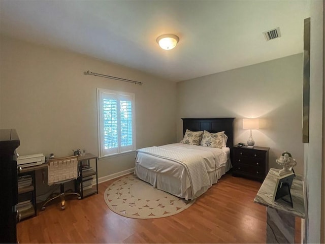 bedroom featuring visible vents, baseboards, and wood finished floors