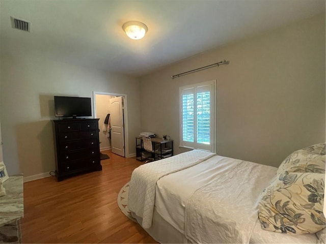 bedroom featuring wood finished floors, visible vents, and baseboards