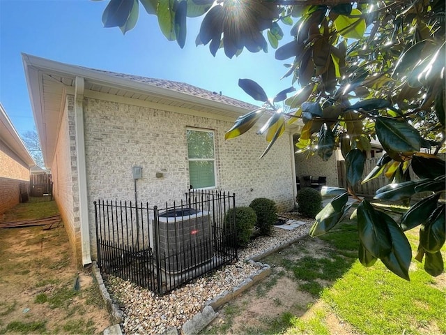 exterior space with brick siding, cooling unit, and fence