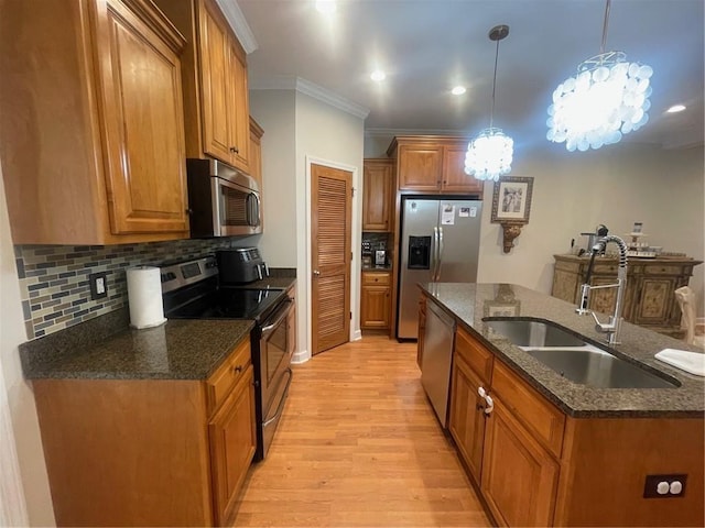 kitchen with stainless steel appliances, a sink, ornamental molding, light wood-type flooring, and brown cabinets