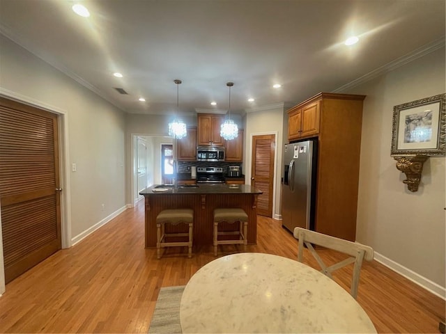 kitchen featuring light wood finished floors, baseboards, visible vents, a breakfast bar, and stainless steel appliances