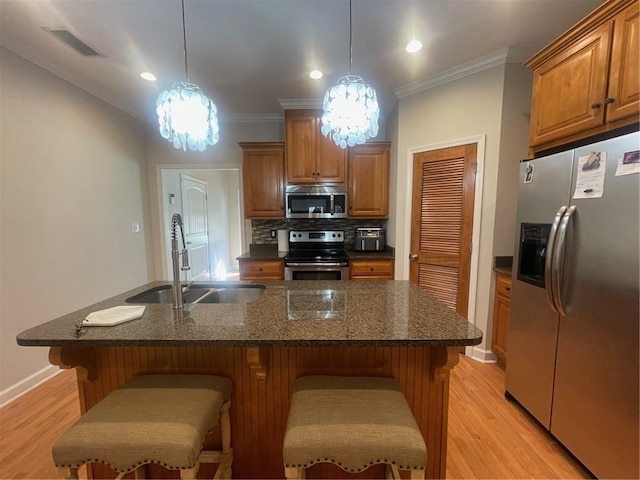 kitchen featuring appliances with stainless steel finishes, brown cabinetry, a sink, and visible vents