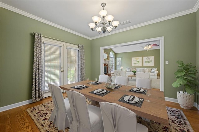 dining area with hardwood / wood-style floors, ceiling fan with notable chandelier, and ornamental molding