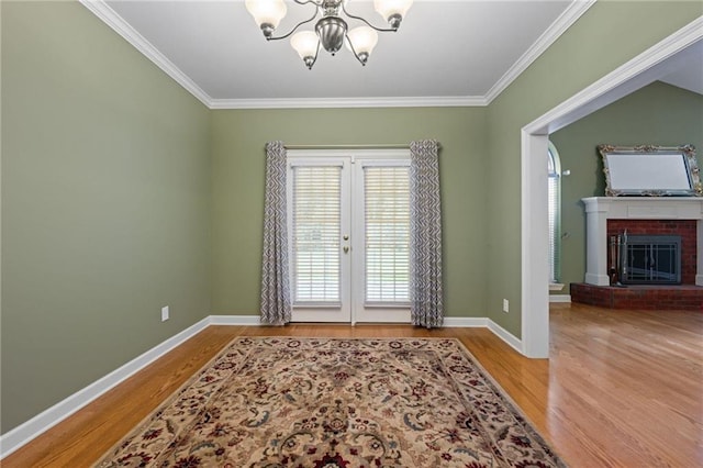 interior space with a notable chandelier, ornamental molding, hardwood / wood-style floors, and a brick fireplace