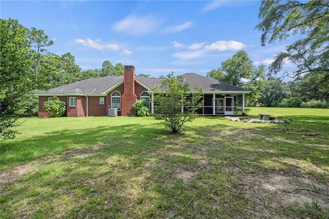 back of house with a sunroom and a lawn