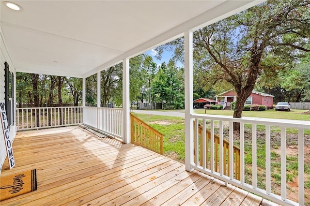 wooden terrace featuring a porch and a yard