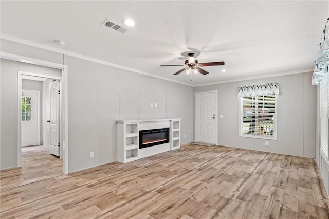 unfurnished living room with crown molding, a healthy amount of sunlight, ceiling fan, and light hardwood / wood-style flooring