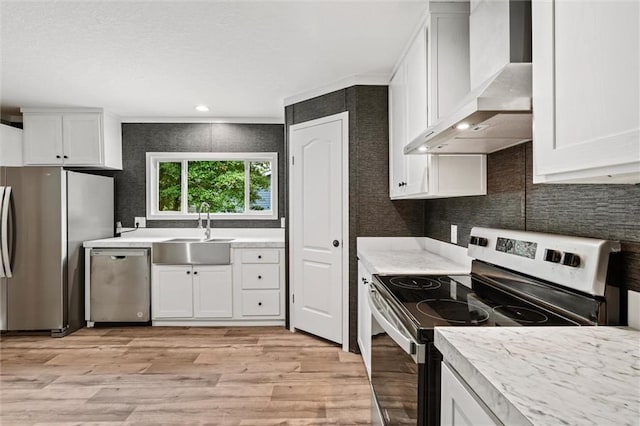 kitchen featuring stainless steel appliances, sink, wall chimney exhaust hood, and white cabinetry