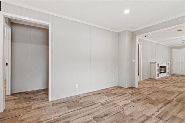 unfurnished living room with crown molding and light wood-type flooring