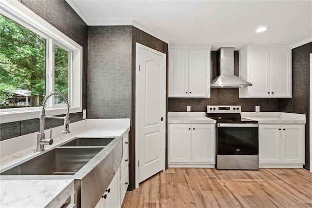 kitchen featuring wall chimney exhaust hood, stainless steel electric stove, sink, and white cabinets