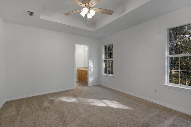 unfurnished room with light carpet, a raised ceiling, and ceiling fan