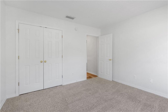 unfurnished bedroom with light colored carpet and a closet