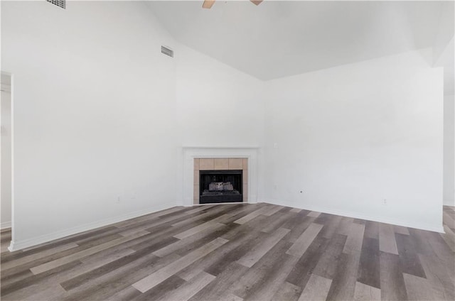 unfurnished living room with hardwood / wood-style floors, ceiling fan, lofted ceiling, and a tile fireplace