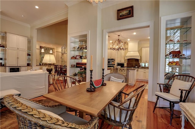 dining room with a chandelier, crown molding, light hardwood / wood-style flooring, and a towering ceiling