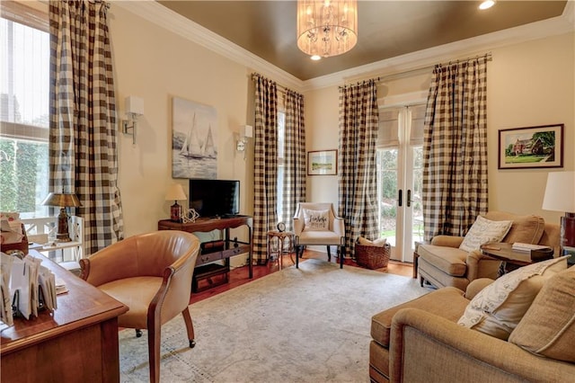 living room with ornamental molding, plenty of natural light, an inviting chandelier, and light hardwood / wood-style flooring