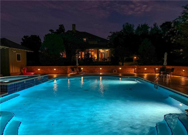 pool at twilight with an in ground hot tub