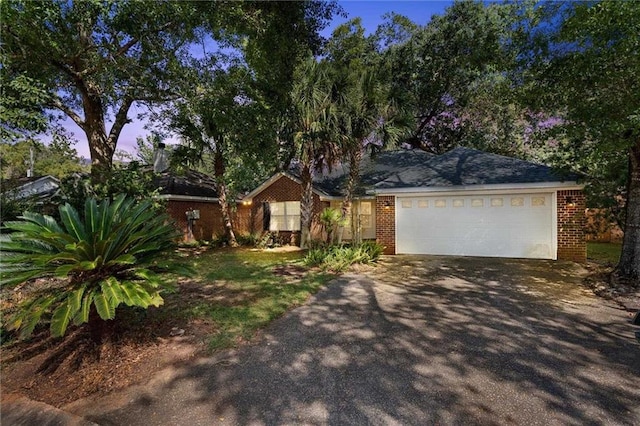 ranch-style house featuring a garage, brick siding, and driveway