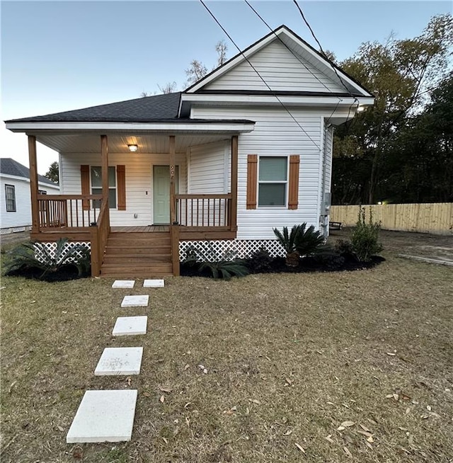 bungalow featuring covered porch and a front yard