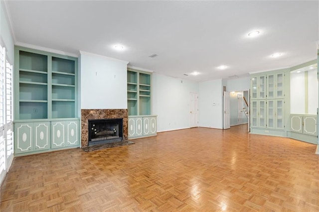 unfurnished living room featuring stairs, crown molding, built in shelves, and a fireplace