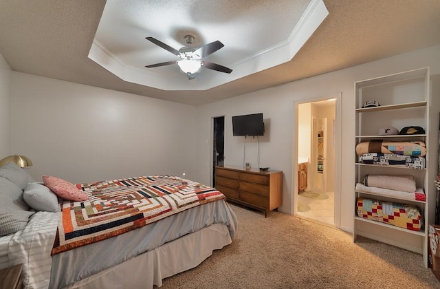 bedroom featuring light colored carpet, ornamental molding, a ceiling fan, a tray ceiling, and connected bathroom