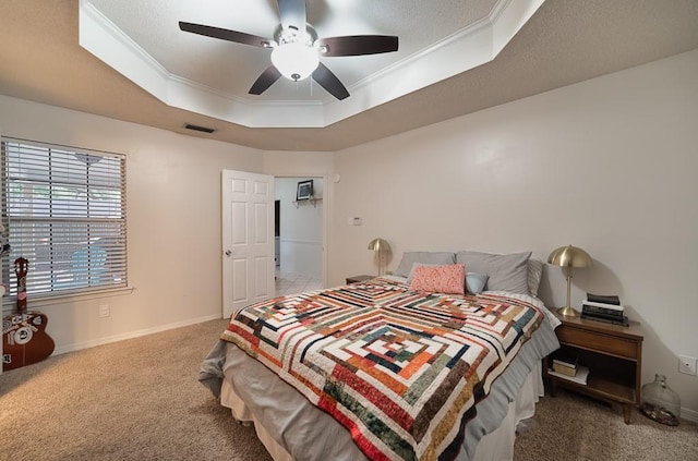 bedroom with a tray ceiling, crown molding, carpet flooring, and visible vents