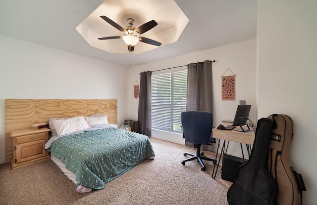 bedroom featuring ceiling fan, a raised ceiling, and carpet