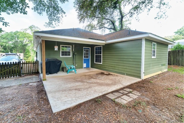 rear view of property with fence and a patio area