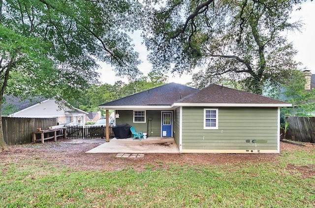 rear view of house featuring a fenced backyard, a patio area, a shingled roof, and a yard