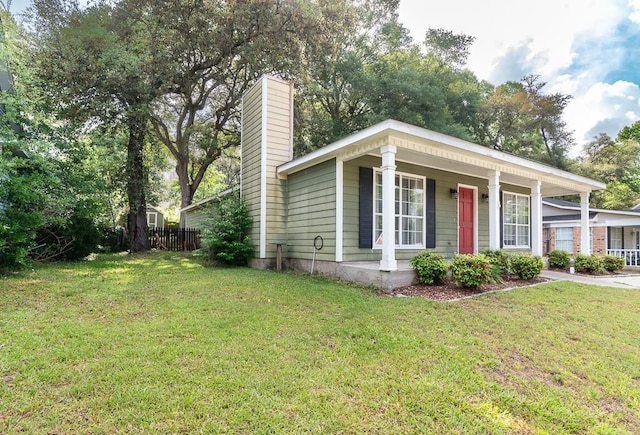 view of home's exterior featuring a chimney, covered porch, fence, and a lawn