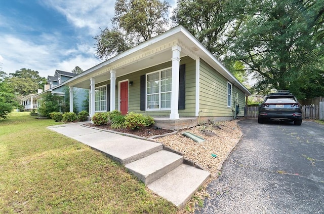 view of front facade featuring a porch, a front lawn, and fence