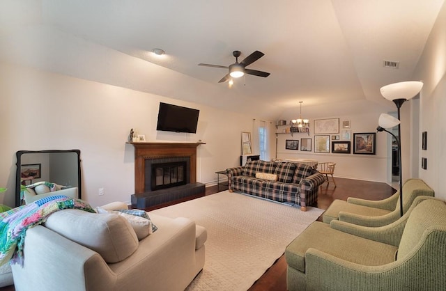 living area with visible vents, lofted ceiling, ceiling fan with notable chandelier, and a brick fireplace