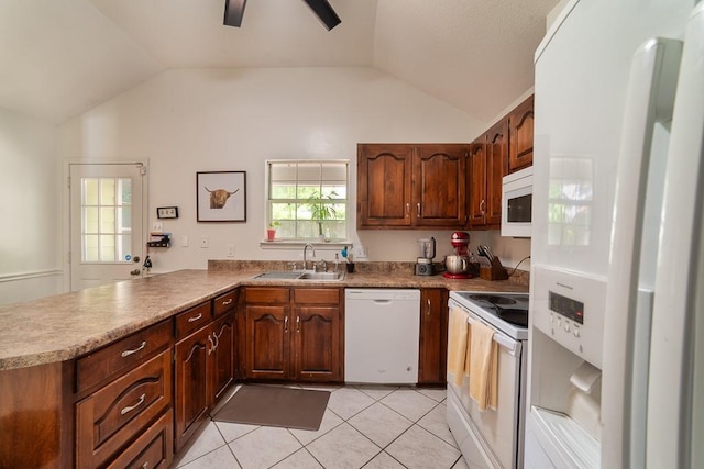 kitchen featuring a sink, vaulted ceiling, a peninsula, and white appliances