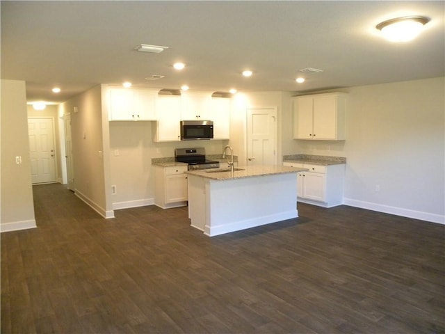 kitchen with light stone countertops, appliances with stainless steel finishes, a kitchen island with sink, sink, and white cabinets